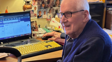 Photo of Hal in his home, sitting at a computer